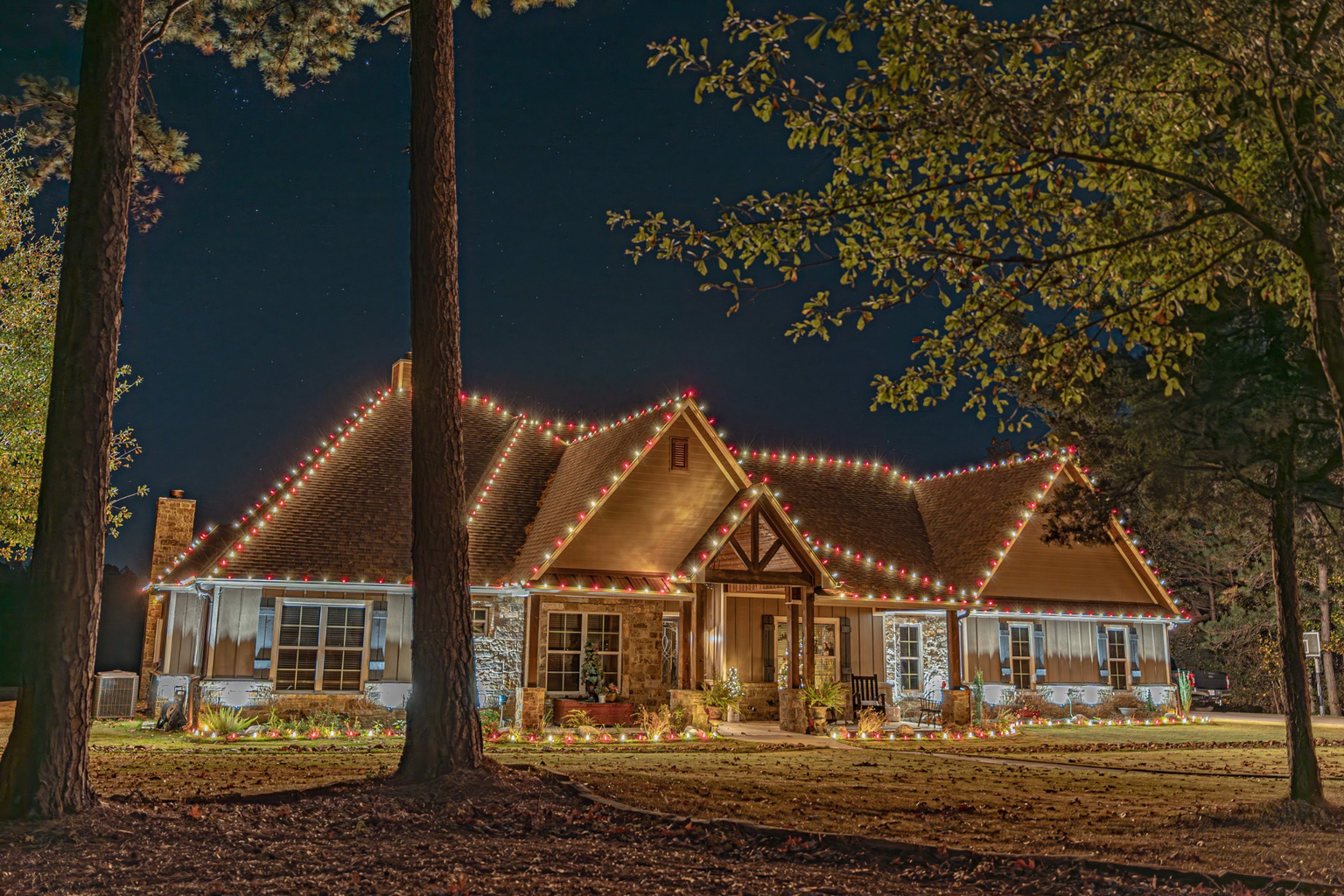 The same house at night, glowing with professionally installed Christmas lights